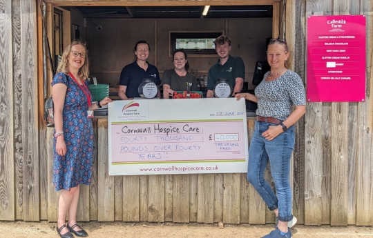 Four members of Trevaskis Farm team happily receiving a large cheque for £40,000 from Erica Vitai, in their fruit sale shed.